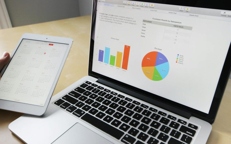 Laptop displaying charts and graphs with tablet calendar for data analysis and planning.