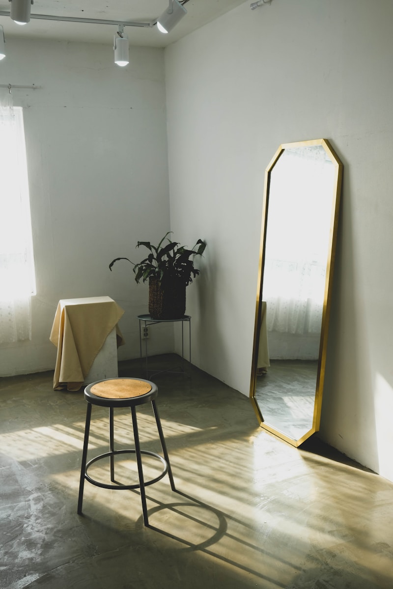 round brown wooden stool near leaning mirror